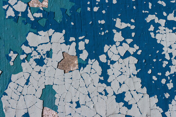 Fototapeta premium Peeling paint on the wall. Old concrete wall with cracked flaking paint. Weathered rough painted surface with patterns of cracks and peeling. Grunge texture for background and design. High resolution.