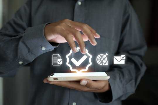 A person is using a smartphone with glowing digital check marks and icons, representing a task completion or digital validation.