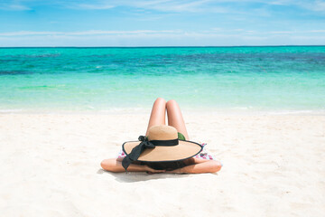 Asian Women tan skin being sunbathes comfort posture with center position on the beach with the seaside background. Comfortable holiday vacations and relaxing travel concept.