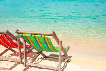 Beach chairs or deckchairs on the tropical white sand beach with seaside near the sea in the daytime with the clear area and light blue sea. Summer holiday and vacation concept for tourism. Copy space