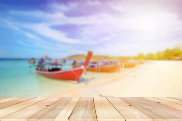 Wooden board empty table on the front with blurred line of Traditional Thai long-tail boat moor on the beach at the sea. Wooden for product or goods