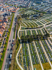 Aerial view of a cemetery with symmetrical rows of graves, a central round building, and surrounding greenery. Pathways and trees create an organized, peaceful layout from above.