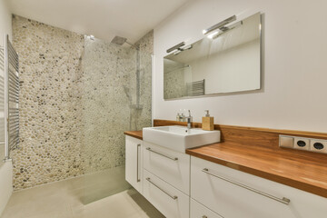 Elegant modern bathroom featuring a sleek sink, wooden accents, and a stylish tile wall, creating a tranquil ambiance suitable for relaxation.