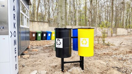 Colorful recycling bins in a forested urban area near a parking meter, with labels for mixed waste,...