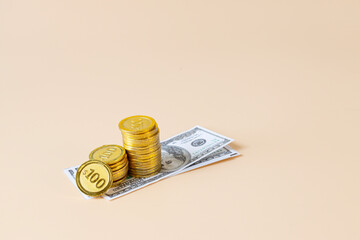 Isolated stack of gold coin and notes on coloured background.