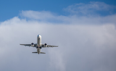 Ein weißes Passagier Flugzeug  A321 nach dem Start, Räder im Einfahren, Fahrwerksklappen geöffnet, vor strahlend blauem Himmel. Dynamik und Eleganz der Luftfahrt in Aktion.