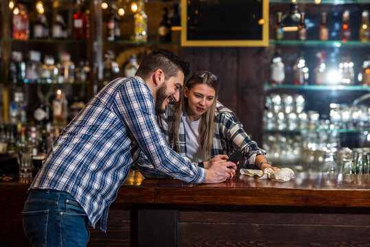 Bartenders, a waiter and a waitress, sit alone at the bar before the opening of a cafeteria or concept restaurant, before the start of business hours, talking and negotiating, expecting customers.