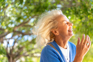 Happy senior woman laughing outdoors, enjoying retirement in nature