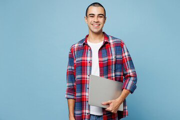 Young happy fun smart IT middle eastern man he wearing red shirt casual clothes hold closed laptop...