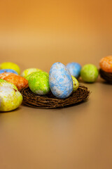 The brightly colored eggs surround a wicker basket placed on a straw bed. A scene celebrating Easter.