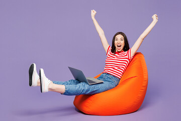 Full body young IT woman wear red striped t-shirt casual clothes sit in bag chair hold use work on...