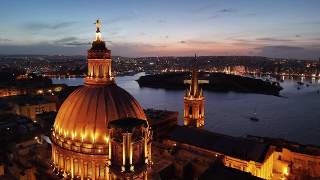  Valetta stunning aerial view at sunset with golden lights illuminating the skyline and tranquil waters
