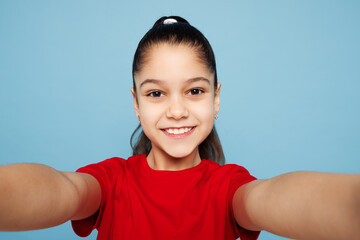 Close up little child kid girl 8-9 years old wears red t-shirt have fun doing selfie shot pov on...