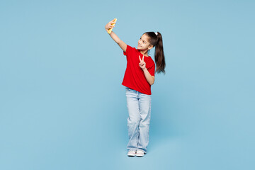 Full body little child kid girl 8-9 years old wearing red t-shirt have fun doing selfie shot on mobile cell phone isolated on blue color background studio. Mother's Day love family lifestyle concept.