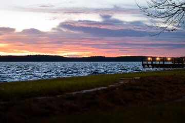 Landscape at the lake Müritz during sunset. Beautiful colorful sky in the evening. Wooden pier building to walk over the water in Waren, Germany. Waterfront of the Binnenmüritz during winter season.