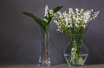 Bouquets of spring flowers lilies of the valley in glass vases.