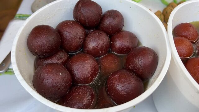 Close up shot of Indian sweet dish Kala Jamun served in white container.