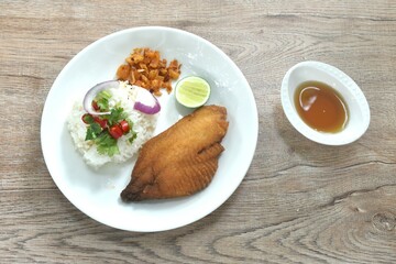 deep fried slice bass fish with rice topping chili and shallot dressing sweet fish sauce on plate  