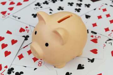 Piggy bank on many playing cards close-up.