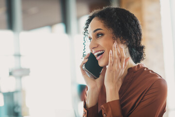 Young businesswoman smiling and talking on phone in bright modern office environment