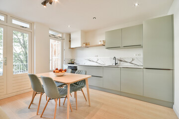 A sleek and contemporary kitchen featuring minimalist design with muted cabinetry and natural lighting, creating a cozy atmosphere for cooking and dining.