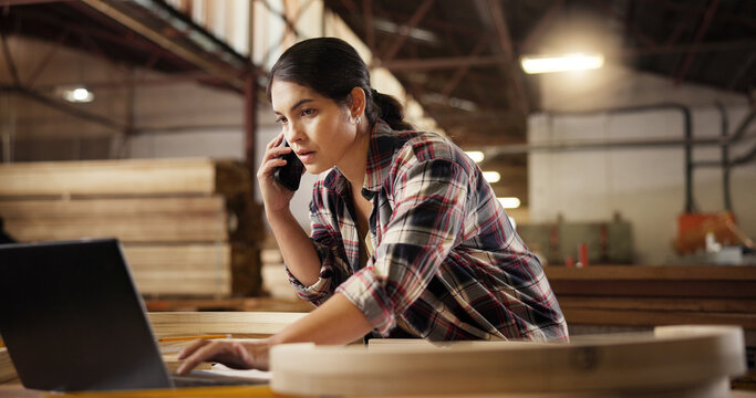 Phone call, carpentry and woman in workshop talking for furniture, manufacturing and lumber renovation. Computer, factory and carpenter on smartphone for online orders, inventory and timber stock