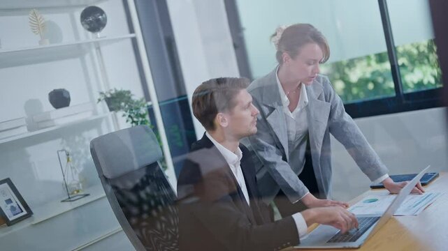 Business professionals collaborate in a modern office setting while analyzing data on a laptop