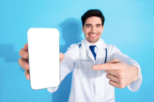 Healthcare professional showing a smartphone with a blank screen on a blue background, emphasizing technology in modern medical practices.