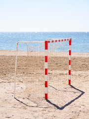 Empty soccer goal standing on sandy beach by the sea