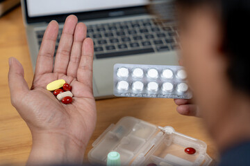 Rear view of a businessman taking pain relief medication after long hours of desk work