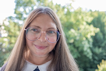 Fototapeta na wymiar close-up stylish charismatic mature woman wearing glasses with long brown hair, age-related changes, smiling confidently, positivity and enthusiasm, positive energy