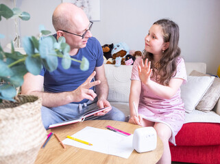 Caucasian family, man 50 years old and girl 9 years old, preparing homework, help from parents.