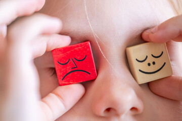 Wooden blocks with emotions, Child's hand playing with wooden blocks, emotional intelligence in...