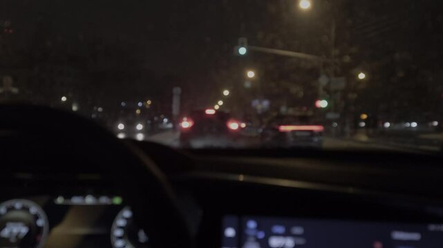 A blurry view of a car's dashboard with a speedometer showing a speed of 60 mph. The car is driving down a dark street at night