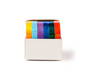 A box of colorful tape for gift wrapping is sitting on a white background. The tape has glamour...