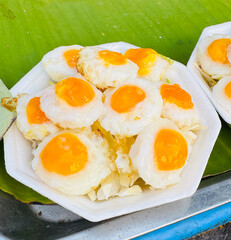 The image features a white octagonal plate arranged with small, round cooked items that resemble miniature sunny-side-up eggs.
