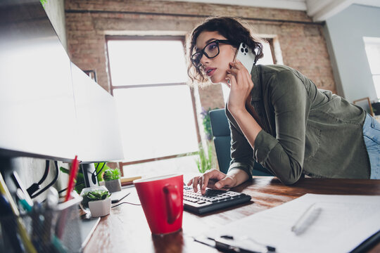 Young professional woman working in a modern home office, multitasking with a phone and computer in a stylish environment