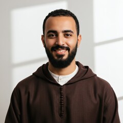 Obraz premium A portrait of a smiling man wearing a traditional brown hoodie and white shirt in studio.