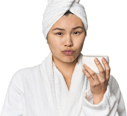 Chinese woman with moisturizer in robe shrugs shoulders and open eyes confused.