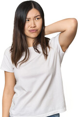 Fototapeta premium Young Chinese woman touching back of head, thinking and making a choice.