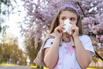 Little blonde girl coughs and covers her mouth with a handkerchief, sick with allergies or a virus...
