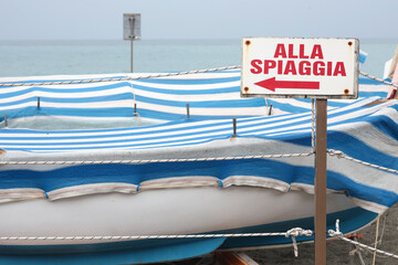 Signpost near boat on beach.Nature and recreation. Sea transport. Passage to beach.