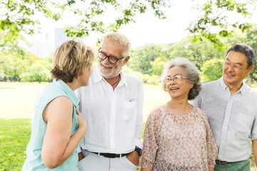Group of four seniors enjoying a sunny day in the park, smiling and chatting. Diverse elderly friends, outdoor gathering, happy and relaxed atmosphere. Group of elderly people friends in park.