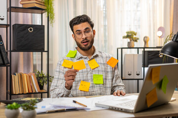 Tired exhausted fatigue young Indian businessman office employee manager sits in home office table...