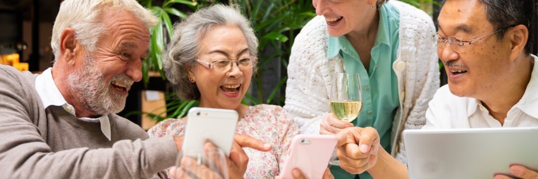 Group of older adults enjoying technology together, smiling and sharing moments. Diverse seniors with smartphones and tablets, engaging and connecting happily. Diverse seniors on social media. - Powered by Adobe