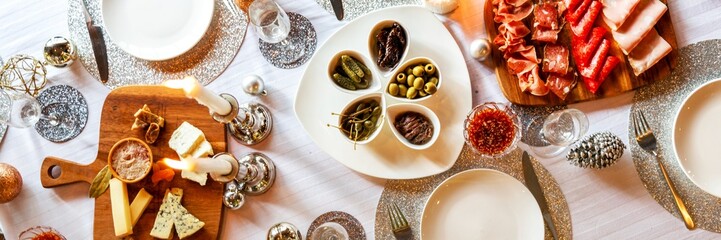 Festive table with assorted meats, cheeses, and olives. Elegant table setting with meats, cheeses, and olives. Holiday spread with meats, cheeses, and olives. Dinner with cold cuts, charcuterie board.