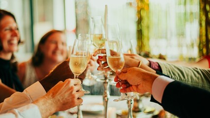 Group of diverse people clinking champagne glasses in Dinner celebration. Festive atmosphere with...