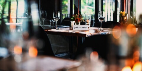 Cozy restaurant with a reserved table. Elegant tableware, reserved sign, and warm lighting create...