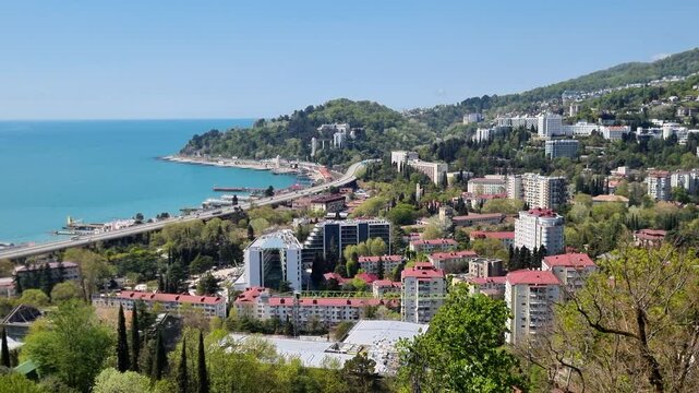 Sochi coastline panorama revealing modern buildings nestled among verdant landscape, showcasing urban development within natural setting