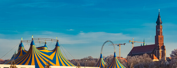 A church and yellow blue circus tents on a sunny winter day at Straubing, Straubing-Bogen, Bavaria, Germany © Martin Erdniss